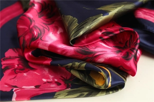 Macro view of silky floral print scarf with navy base and vibrant red flowers