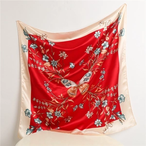 Detail of red square silk scarf featuring butterfly floral patterns and satin texture