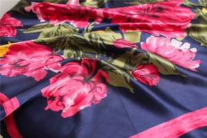 Detail of floral silk scarf showing vibrant pink flower prints and smooth satin texture