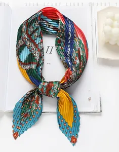 Détail d'un foulard plissé en soie avec des motifs géométriques colorés posé sur un magazine