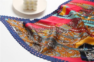 Détail du foulard en soie plissé avec motifs artistiques de selle multicolores