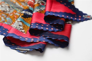 Détail du foulard en soie plissée aux motifs colorés et bordures décoratives en zigzag