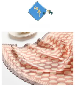 Macro detail of pleated silk scarf showing peach pink polka dots and smooth texture
