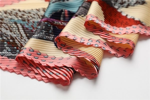 Détail d'un foulard en soie plissé montrant les plis accordéon et le motif selle