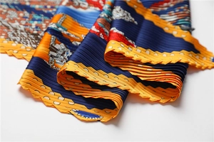 Détail d'un foulard plissé en soie aux motifs géométriques vibrants et plis accordéon précis