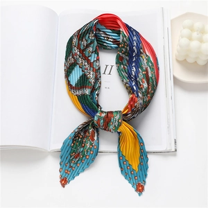 Foulard plissé coloré aux motifs géométriques posé sur un magazine blanc avec décoration