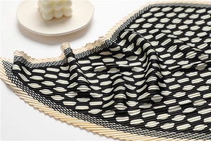 Detailed view of black and white polka dot pleated silk scarf on a white tray