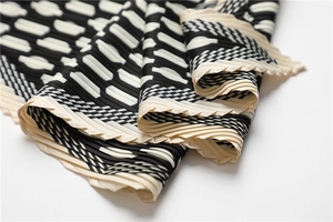 Detail of pleated silk scarf with black and white geometric patterns and sharp accordion folds