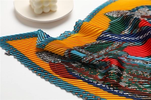 Détail macro du foulard en soie plissé aux motifs exotiques et textures colorées