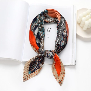 Détail d'un foulard plissé en soie avec motifs bohèmes orange et bleu sur magazines
