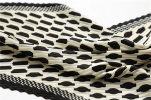 Detail shot of the pleated texture and black geometric pattern on the silk scarf