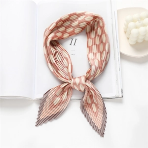 Pleated polka dot silk scarf in peach and grey displayed on a white fashion magazine