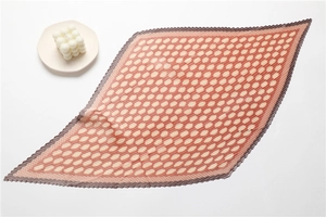 Detailed view of pleated silk scarf featuring orange geometric dot patterns and dark edges