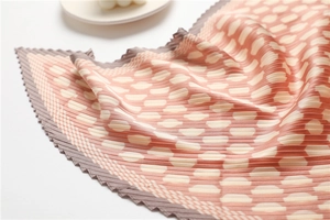 Detail of pleated silk scarf featuring pink and brown polka dot patterns and wavy edges