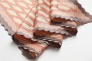 Detail of accordion pleated silk scarf with orange and beige geometric patterns
