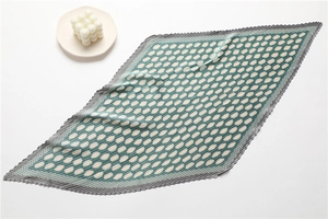Detail of pleated silk scarf featuring green and white geometric honeycomb patterns