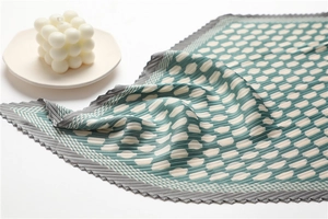 Close-up of pleated silk square scarf with vintage green polka dots and geometric patterns