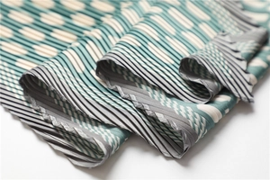 Macro shot of pleated fabric with green and cream geometric polka dot pattern detail
