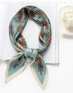 Detailed view of mint green pleated silk scarf featuring vibrant floral patterns and wavy edges