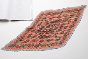 Detail of elegant pleated silk scarf with colorful spots on soft orange fabric