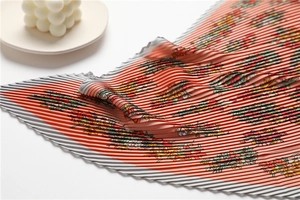 Detail of pleated silk scarf featuring colorful floral prints and soft orange-pink tones