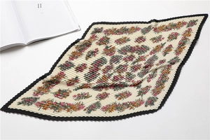 Detail of pleated floral silk scarf with black scalloped edges and elegant pattern