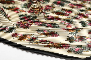 Close-up of pleated silk-like scarf with floral patterns and delicate edge detailing