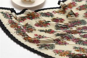 Close-up of pleated silk scarf with vintage floral print and delicate wavy edge detail