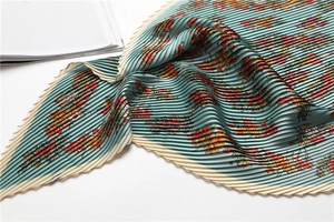 Detail of teal pleated scarf with floral print and fine accordion fold texture