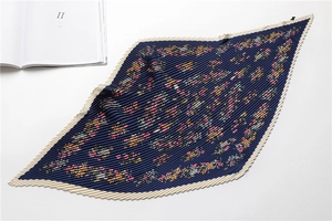 Detail of elegant pleated silk scarf featuring navy blue floral pattern and cream borders