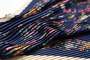 Macro detail of dark blue floral pleated silk scarf showing elegant texture and patterns