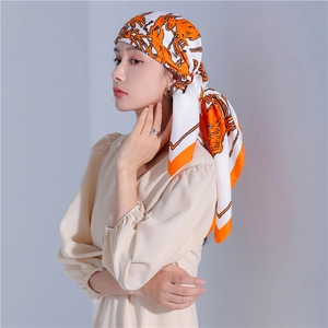 Close-up of a stylish silk scarf with orange horse print worn as a headpiece