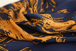 Detailed close-up of dark blue silk scarf with orange horse pattern and smooth texture
