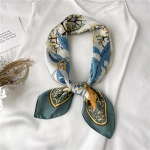 Vue détaillée d'un foulard en soie à motif de feuilles noué sur un débardeur blanc chic