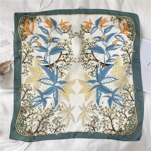 Vue détaillée du motif floral et du large bord vert foncé sur le foulard carré en soie
