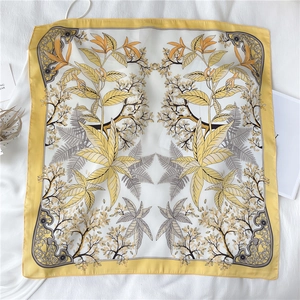 Détail d'un élégant foulard carré en soie avec motifs de feuilles et bordures cousues