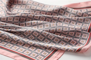 Gros plan d'un foulard en soie rose et gris avec motifs géométriques et texture lisse