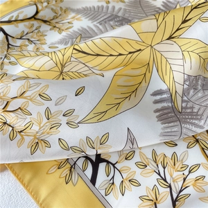 Gros plan d'un foulard en soie à motif feuilles montrant la texture satinée et les ourlets
