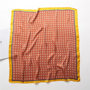 Détail d'un foulard en soie avec motifs géométriques orange et bordures jaunes