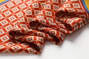 Détail d'un foulard en soie aux motifs géométriques orange et bordure bleue contrastée