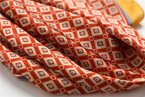 Gros plan détaillé du foulard en soie orange avec motifs géométriques et points bleus