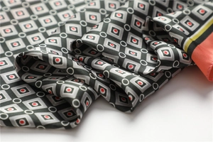 Détail d'un foulard en soie avec motifs géométriques et bordures contrastées corail