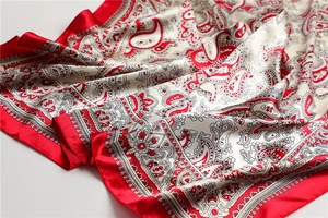 Detail eines Seidenschals mit Paisley-Muster, glänzendem Satingewebe und Faltenwurf