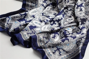 Nahaufnahme eines Seidenschals mit Paisley-Muster in Dunkelblau und glänzender Textur