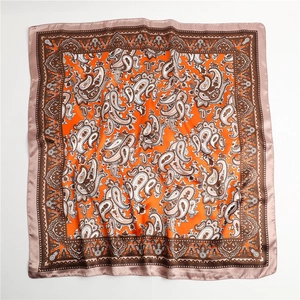 Detailaufnahme des orangefarbenen Seidenschals mit Paisley-Muster und braunem Rand