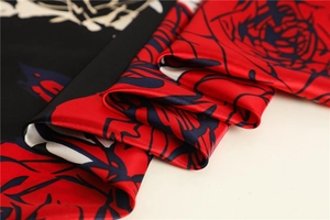 Macro shot of elegant silk scarf showing red rose print texture and glossy satin fabric