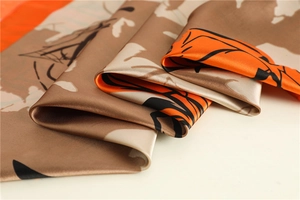 Detailed close-up of glossy floral silk scarf fabric with elegant orange flower print