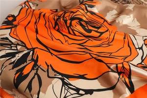 Detail of silk scarf showing vibrant orange rose print and smooth glossy fabric texture