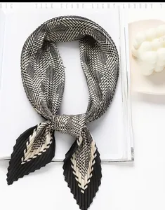 Detailed view of pleated houndstooth silk scarf on a magazine with decorative candle
