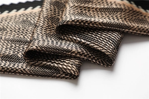 Detail shot of the pleated texture and khaki houndstooth pattern on the silk scarf